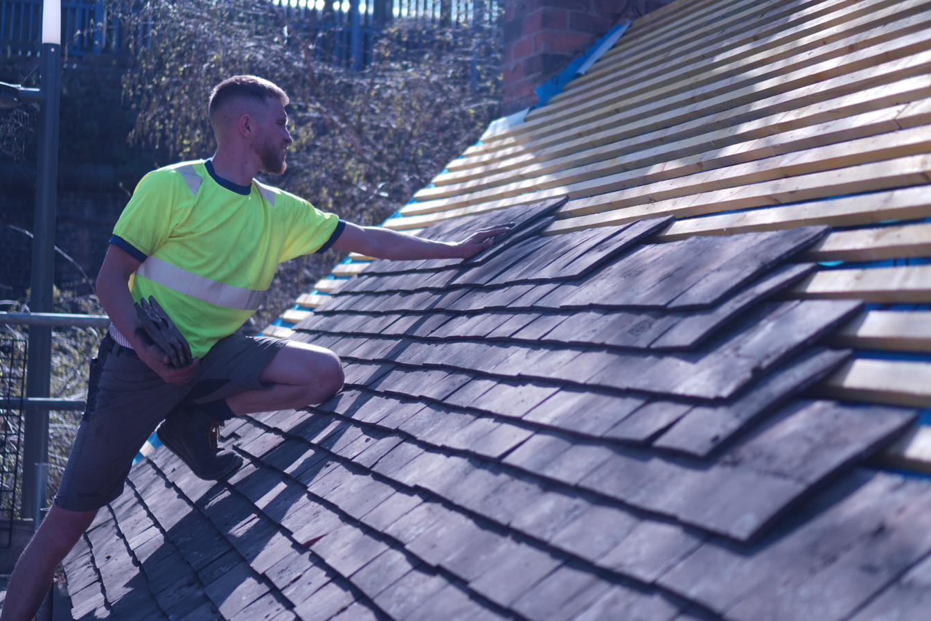 Roofer laying new slates during a pitched roof repair job