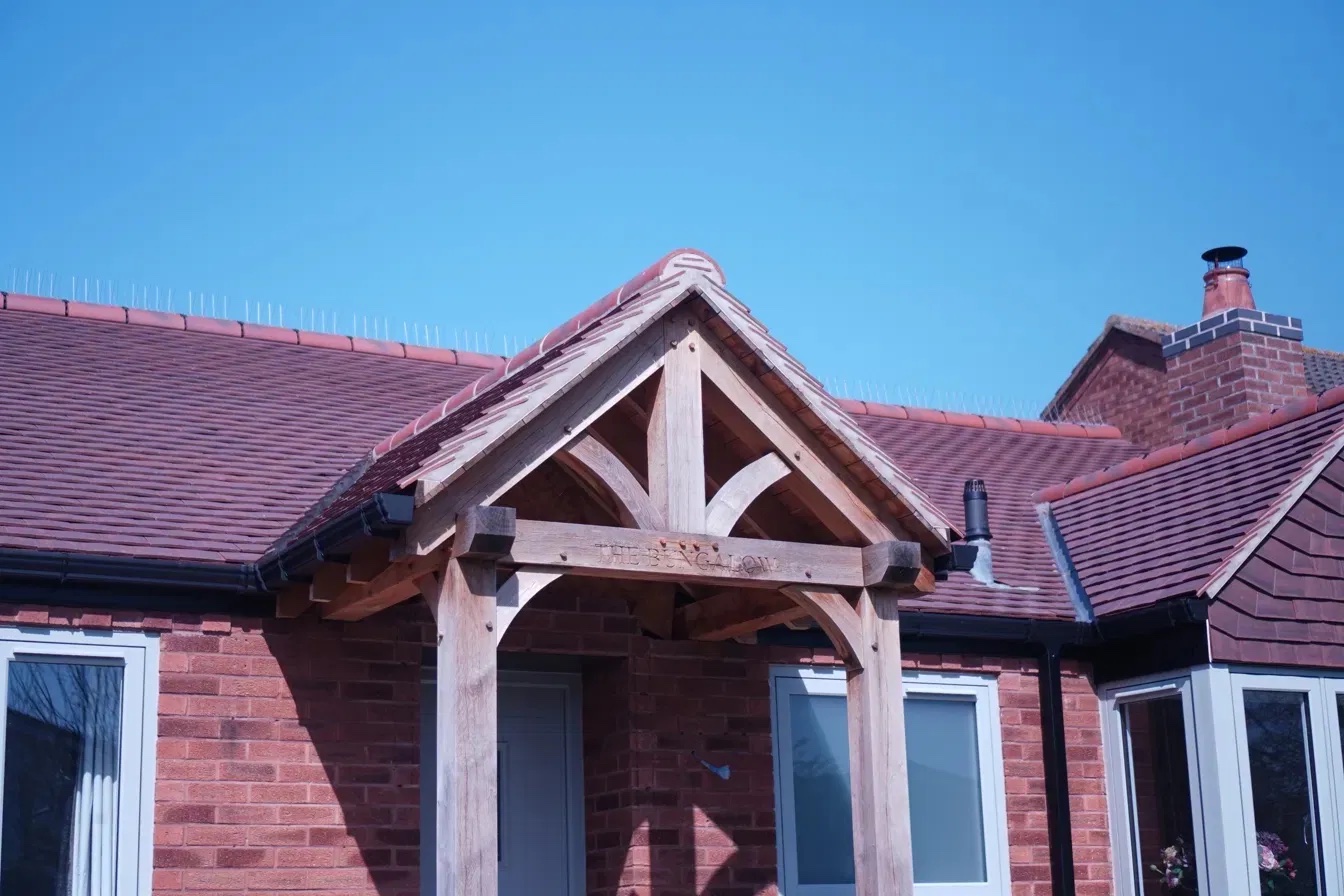 UK bungalow with clay tiled roof, oak porch and black uPVC guttering and fascias