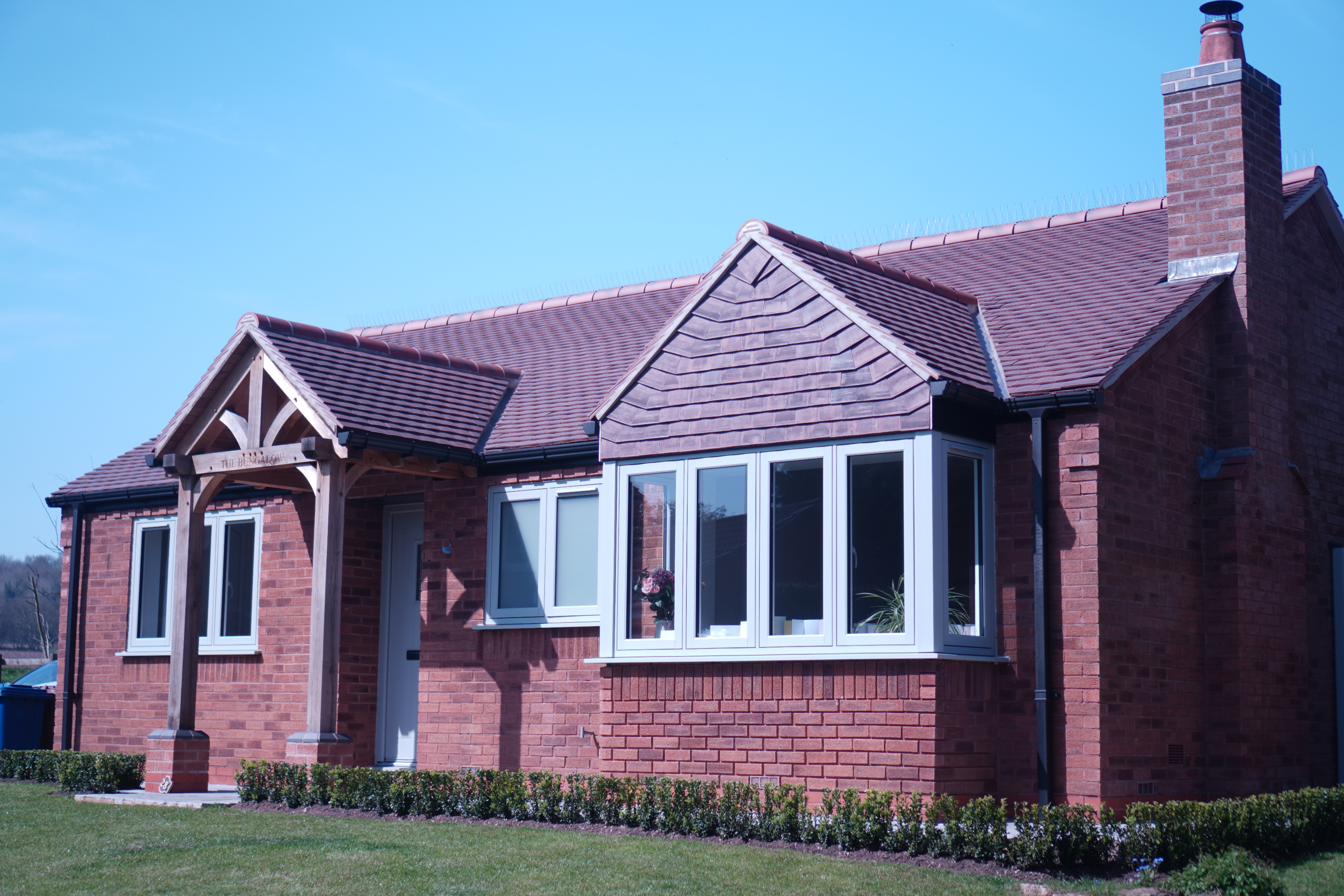 Completed pitched roof on red brick bungalow with oak entrance porch — Swifts Roofing & Construction